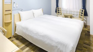 Habitación de hotel con una cama grande, un escritorio, una silla, una mesita y una ventana con cortinas.