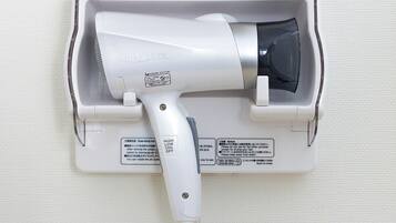 A hair dryer mounted on a wall with a power cord.