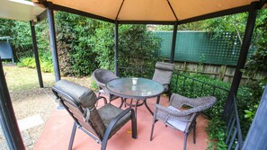 Eine überdachte Terrasse mit einem runden Tisch und vier Korbstühlen.