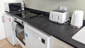 Pieni keittiönurkkaus, jossa on mikroaaltouuni, leivänpaahdin, vedenkeitin ja pieni jääkaappi.