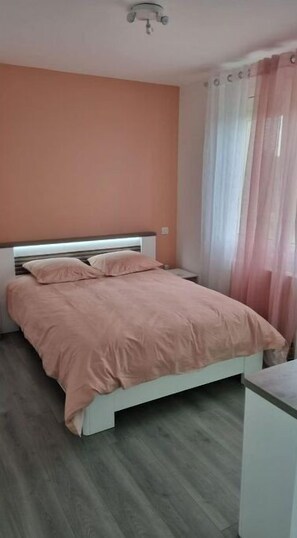 A bedroom with a bed, a nightstand, and a ceiling light fixture.