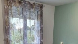 Une chambre à coucher avec un lit, un bureau et une fenêtre avec des rideaux.