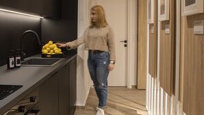 Une cuisine moderne avec un plan de travail noir, un évier et une personne tenant des citrons.
