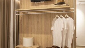 Une chambre d’hôtel avec une armoire en bois, un téléviseur fixé au-dessus, et un lit recouvert d’une couette beige.