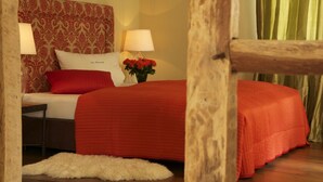 A bedroom with a red bedspread, a white pillow with text, a red pillow, a nightstand with a lamp, and a vase with red flowers. - Landhaus in Idyllischer, Ruhiger Lage und Flughafennähe (Ratingen)