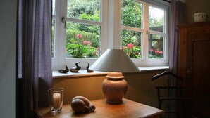 A room with a window, a table with a lamp, a candle, and a vase. - Landhaus in Idyllischer, Ruhiger Lage und Flughafennähe (Ratingen)