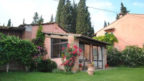 Une maison avec une façade en briques, un porche abrité et un jardin bien entretenu, agrémenté de plantes à fleurs.