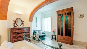 Une chambre à coucher avec un lit, une commode en bois, un miroir, un canapé bleu et une grande armoire en bois.