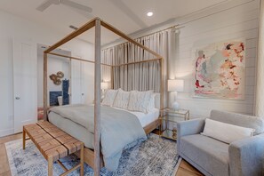 Une chambre à coucher avec un lit à baldaquin, un banc, un canapé gris et un grand tableau abstrait accroché au mur.
