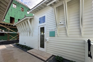 Un bâtiment blanc avec un toit vert, une porte d’entrée et un petit porche.