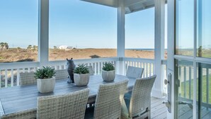 Un espacio de estar techado al aire libre con vistas a la playa y las dunas.