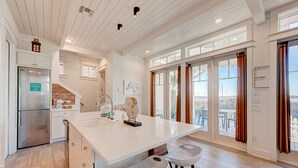 A spacious kitchen with a large island, modern appliances, and large windows offering views.
