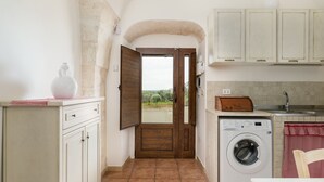 A laundry area with a washing machine, a sink, and a view through an open door.