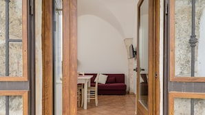 A room with a dining table and chairs, a red sofa, and a wooden door with glass panels.