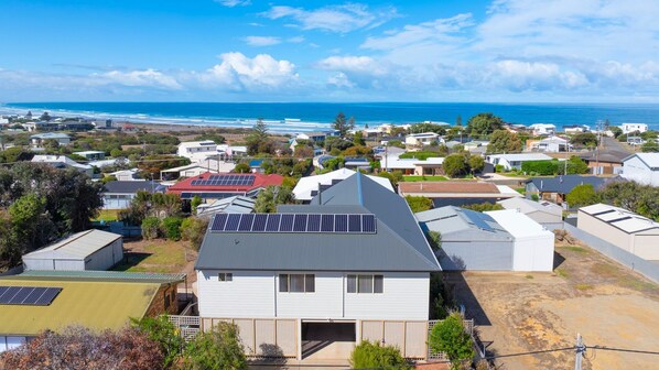 Zona residencial con casas, algunas con paneles solares, y vista al océano.