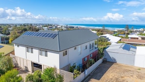 Un quartier résidentiel avec des maisons, dont certaines sont équipées de panneaux solaires, et qui offre une vue sur l’océan.