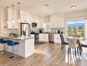 A modern kitchen with white cabinets, stainless steel appliances, and a large island with bar stools.