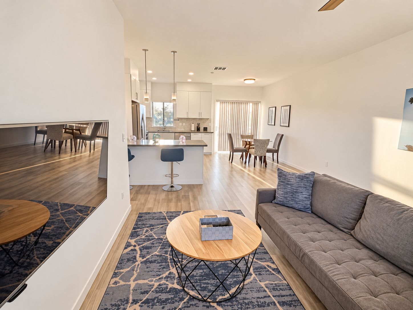 A modern living room with a sofa, a coffee table, and a dining area with chairs and a table.