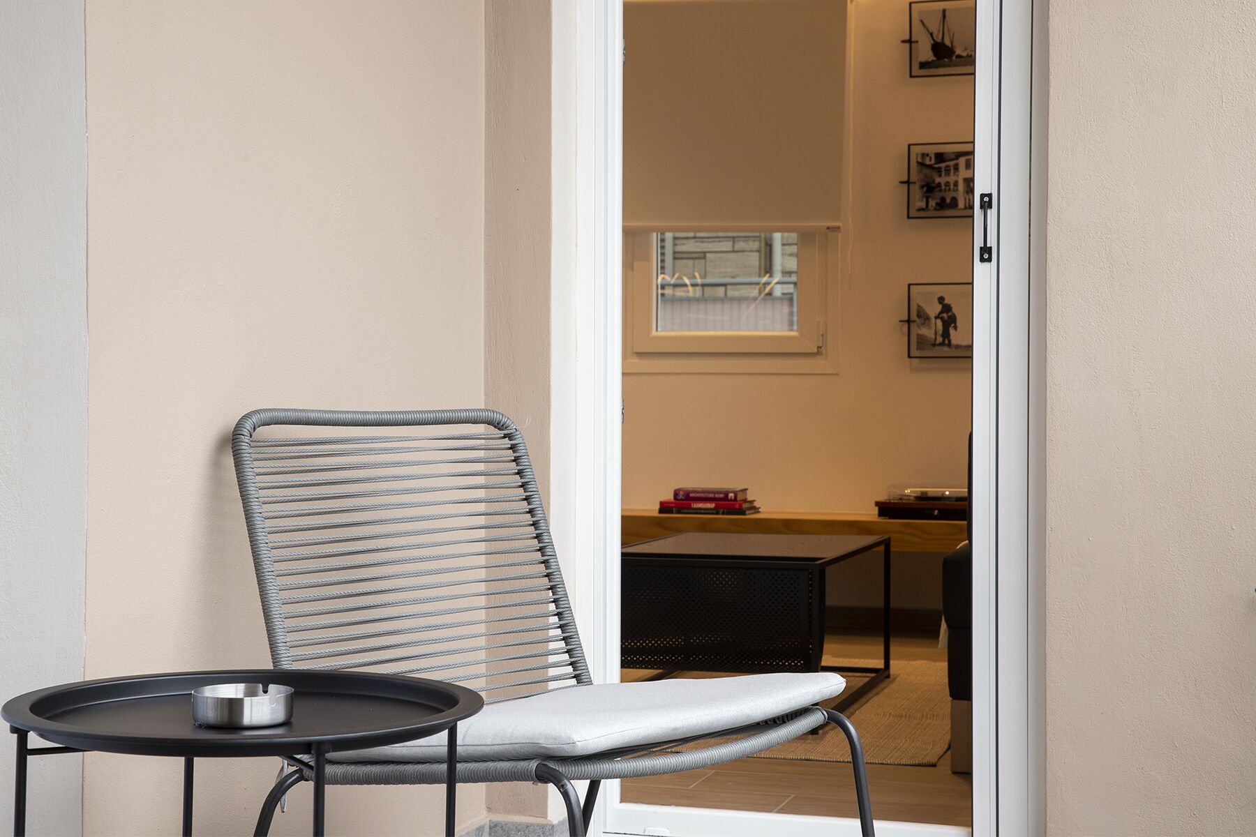A modern chair with a metal frame and a cushioned seat, positioned next to a small round table with a metal ashtray.