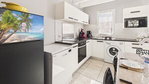 A modern kitchen with white cabinets, a stainless steel refrigerator, a coffee maker, and a washing machine. - Pretty yellow-shutter house w/ terrace for 6 (La Tranche-sur-Mer)