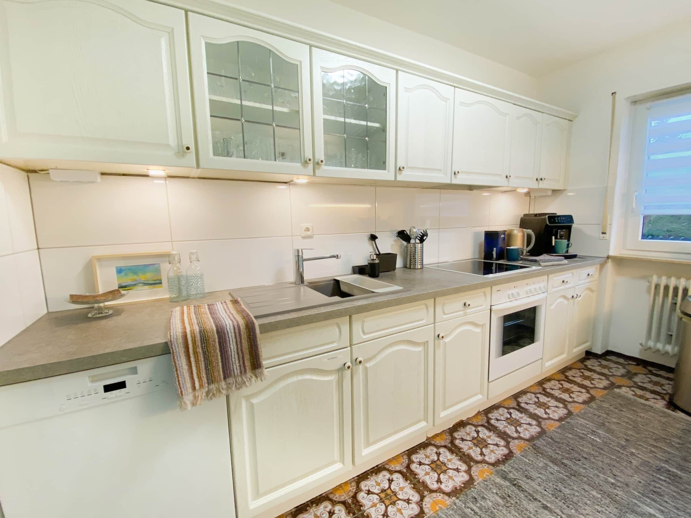 A kitchen with white cabinets, a built-in oven, a coffee maker, and a window with a view.