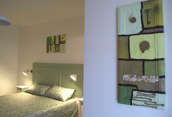 A bedroom with a bed, two bedside lamps, and a wall art piece above the bed.