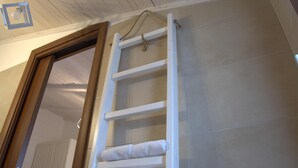 A bathroom with a wooden ceiling, a white towel rack, and a tiled wall. - Racconti di pietra (Conversano)