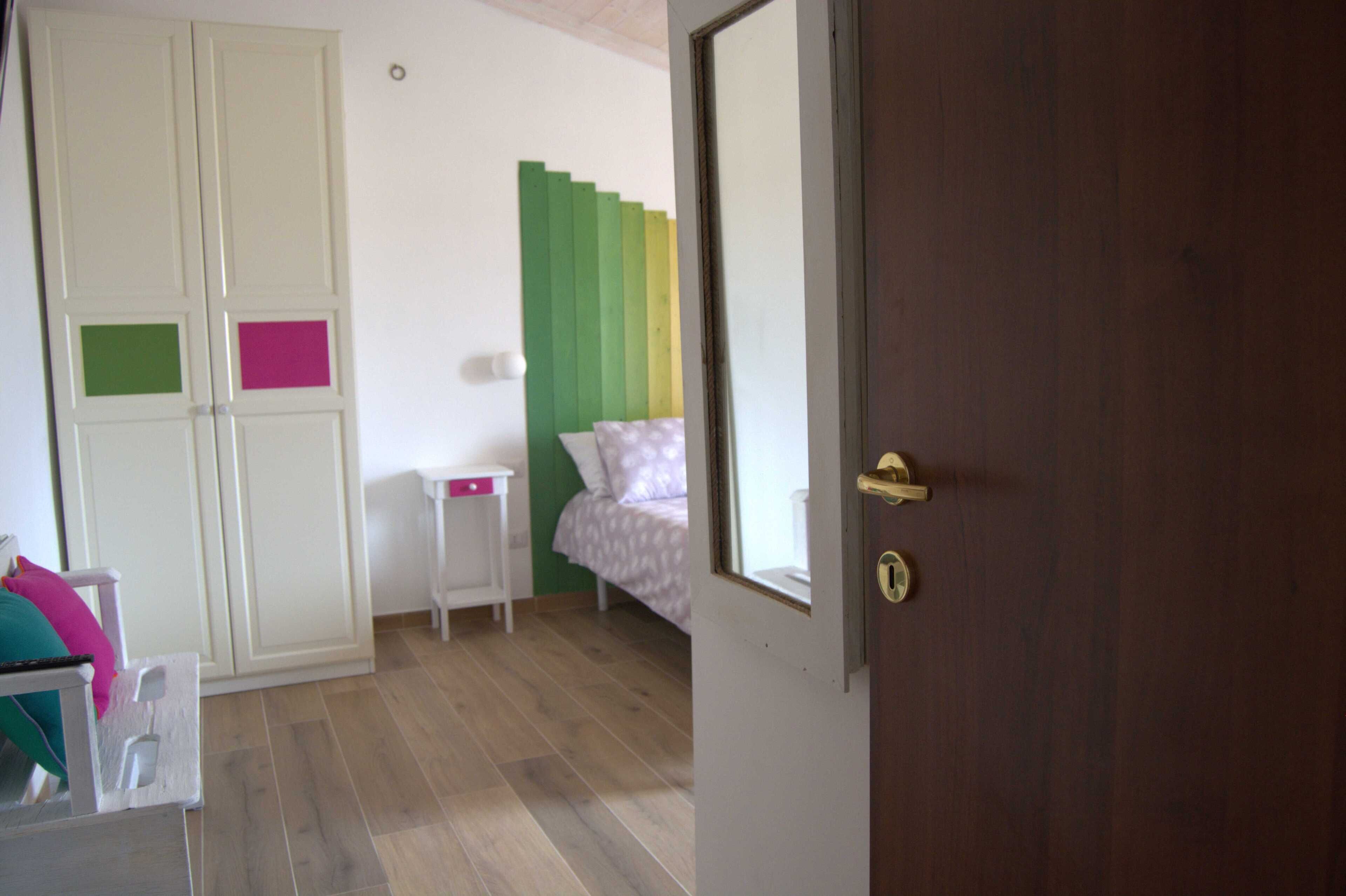 A bedroom with a bed, a nightstand, a wardrobe, and a door.