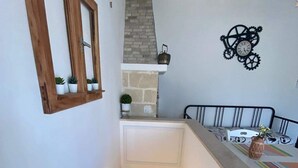 A staircase with a wooden handrail, a small potted plant, and a decorative clock on the wall. - Racconti di pietra (Conversano)