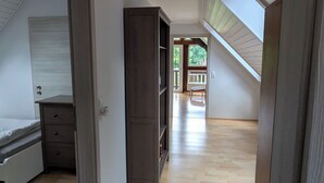 Un pasillo espacioso con suelo de madera, un armario empotrado y vistas a un balcón exterior.