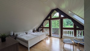Un dormitorio con una cama grande, un escritorio y una silla. Hay ventanas y un balcón con sillas.