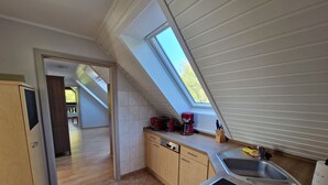 Una cocina con tragaluz, armarios de madera, lavavajillas y un fregadero.