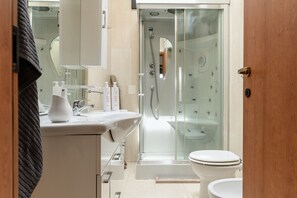 Villa | Badkamer | Een douche, een haardroger, een bidet, handdoeken