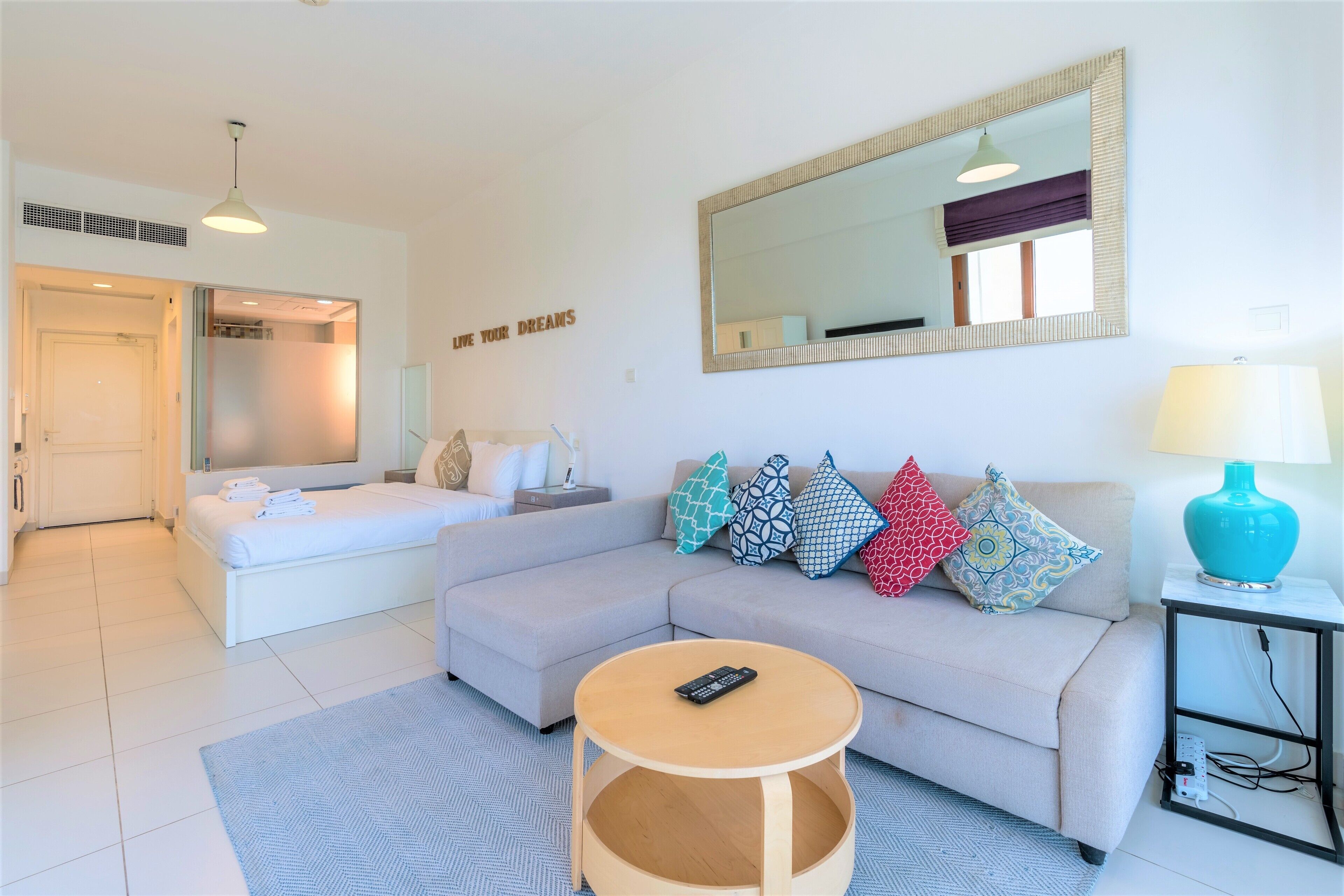 A modern living room with a sofa, a round coffee table, a mirror, and a lamp.