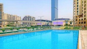 A swimming pool with a view of surrounding buildings and a pedestrian bridge. - Luxurious Studio With Breath-taking Palm Views (Dubai)