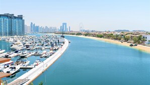 A marina with numerous boats docked, a clear sky, and a city skyline in the background. - Luxurious Studio With Breath-taking Palm Views (Dubai)