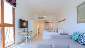 A modern hotel room with a sofa, a desk, a TV, and a bed. - Luxurious Studio With Breath-taking Palm Views (Dubai)