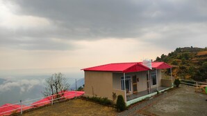 Un edificio de techo rojo, un porche cubierto y vistas a un paisaje montañoso.