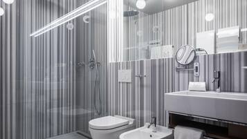 Un baño moderno con cabina de ducha de vidrio, un lavabo blanco y un espejo sobre él.