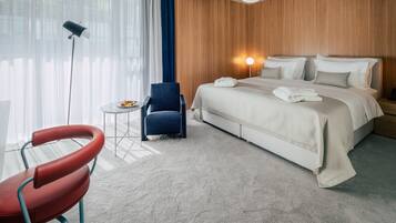 Una habitación de hotel con una cama, una silla, una mesita y una lámpara.