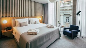 A hotel room with a large bed, bedside lamps, a chair, and a view of a building through the window. - Met Boutique Hotel (Zagreb)