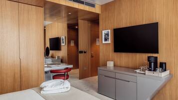 Una habitación de hotel con cama, escritorio, silla, televisor y cafetera.