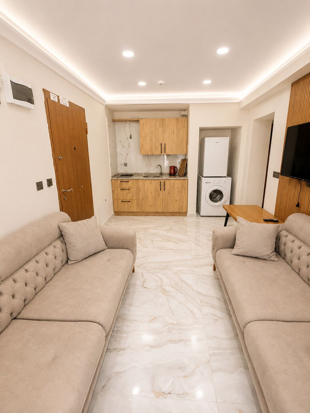 Un salon moderne avec un canapé, une table basse et un téléviseur fixé au mur.