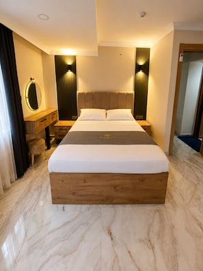 A modern bedroom with a large bed, wooden nightstands, a round mirror, and wall sconces.