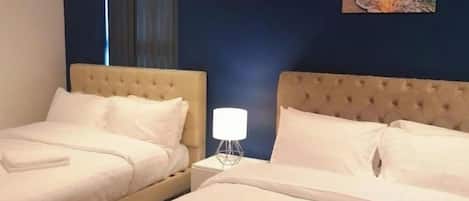 Une chambre d’hôtel avec deux lits, une table de chevet avec une lampe et un tableau représentant un coucher de soleil accroché au mur.