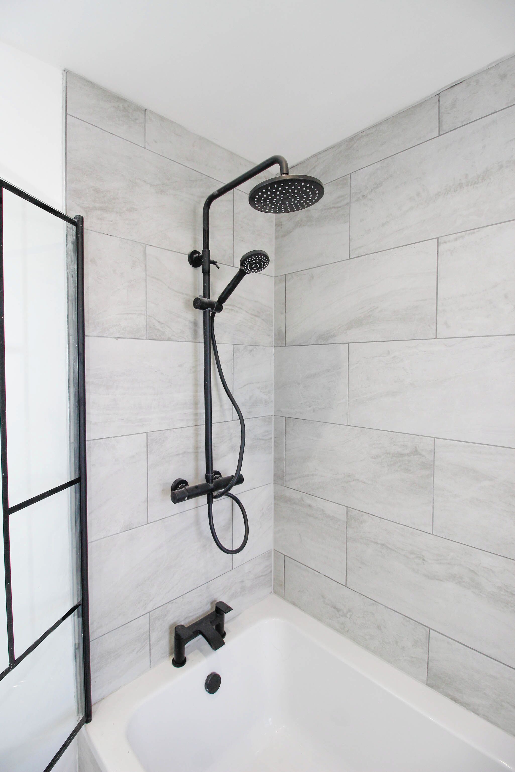 A modern bathroom with a shower, a bathtub, and tiled walls.