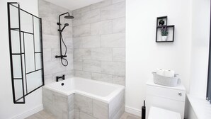 Ein modernes Badezimmer mit Eckdusche, einer weißen Badewanne und Toilette.