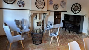 Una sala de estar acogedora con suelo de baldosas de piedra, chimenea y varios relojes en la pared.