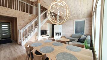 A wooden interior with a dining area, sofa, and staircase.
