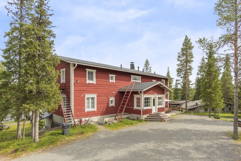 A red wooden house with a porch, a ladder, and a bicycle.